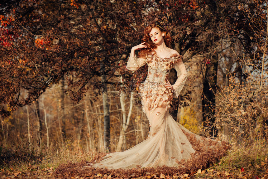 美丽优雅的女人站在秋天的森林里穿着雪佛龙礼服图片