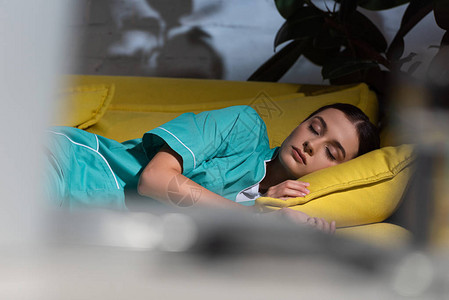 有吸引力的穿制服睡在黄沙发上夜间值夜班的护士有图片