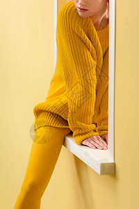 穿着黄色毛衣和紧身裤坐在装饰窗图片