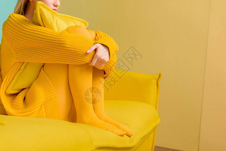 穿着黄色毛衣和坐在黄色沙发上穿图片