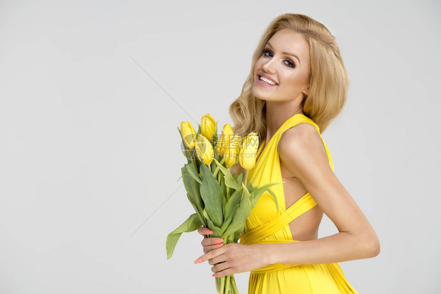 穿黄色洋装的美丽金发美女手拿着黄图片