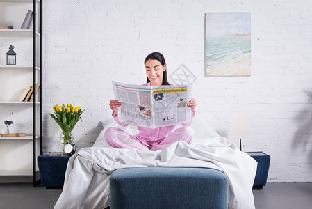 穿着睡衣在家中床上阅读报图片