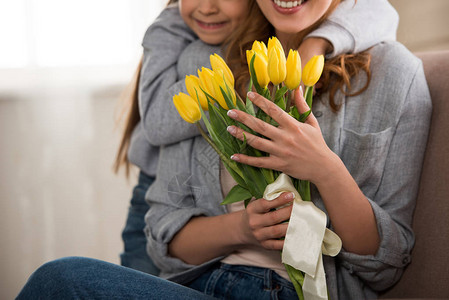 怀着黄色郁金香的微笑的母亲拥抱图片