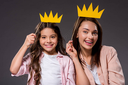 女儿和母亲带着纸冠在灰色上图片