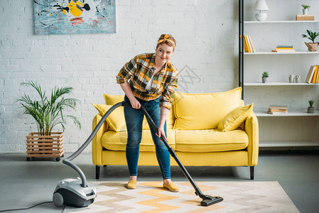 美丽的女人在家用吸尘器清洁地毯图片
