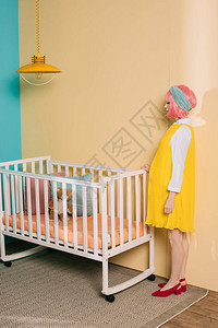 在儿童房靠近婴儿床的复古风格孕妇别针的侧视图图片