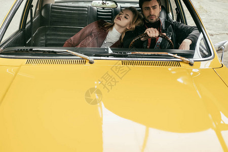 坐在黄色反向车厢中时尚年轻夫妇的高图片