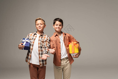 两个微笑的兄弟拿着蓝色和黄色的礼盒图片