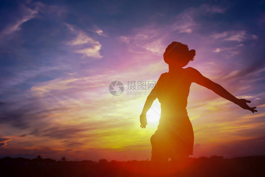 一个幸福的女人和日落的剪影图片