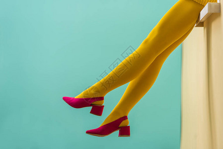穿黄色紧身裤和穿着蓝色背景粉红色鞋的妇图片