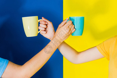 蓝色和黄色背景妇女手中彩色杯图片