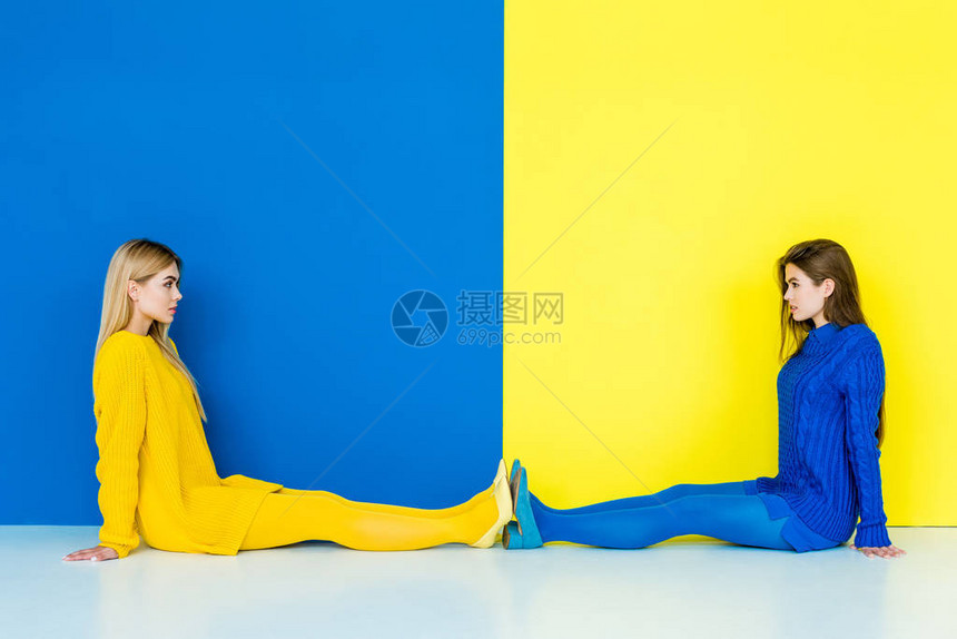 女时装模特坐在地板上在蓝色和黄色背图片