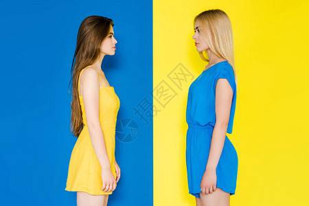 女时装模特儿互相孤立地看待对方的蓝色背景图片
