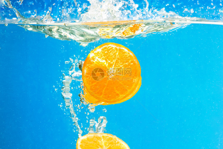蓝色背景水中溅起的柑橘片图片