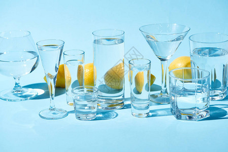 蓝色背景中带水和整个柠檬的透明眼镜图片