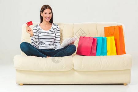信用卡购买的年轻女坐在沙发上图片