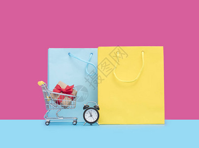 小型购物车和粉红色背景的闹钟袋小购物图片