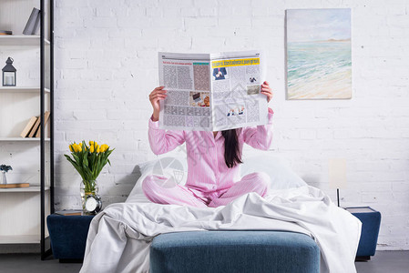 穿着睡衣和在家床上报纸上登报纸的妇图片