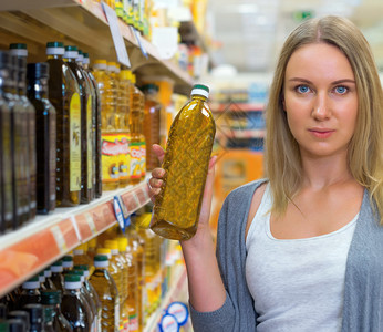 在杂货店挑选橄榄油的女人图片