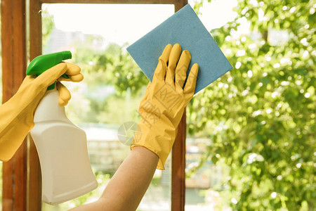 穿黄色手套的女孩用洗涤剂洗刷塑料窗户图片