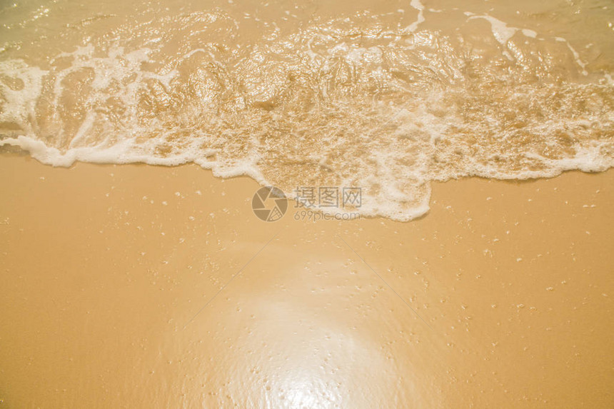 在湿黄沙的海浪与太阳光芒图片