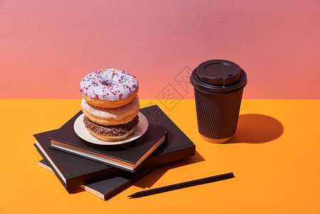 碟子上的美味甜圈和笔记本附近的纸咖啡杯图片