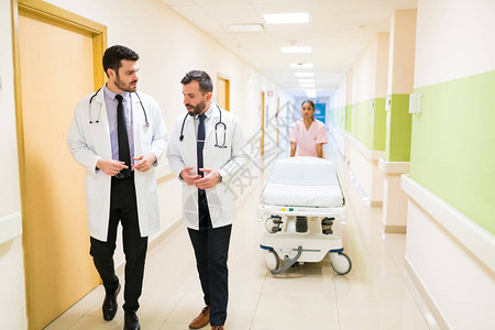 男医生讨论护士在医院走廊推轮床时图片