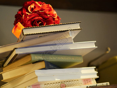 成堆的书上放了一束玫瑰图片