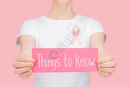 戴着粉红乳腺癌标志的女孩双手拿着粉红色卡片图片