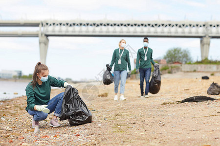 一群志愿者在户外河岸边捡起垃圾在图片