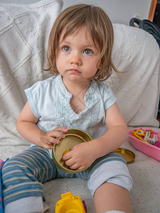 两岁迷人的女婴穿着舒适的衣服在家里的沙发上玩她的玩具图片