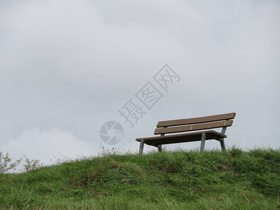 一张长椅孤零零的在草坡上背景图片