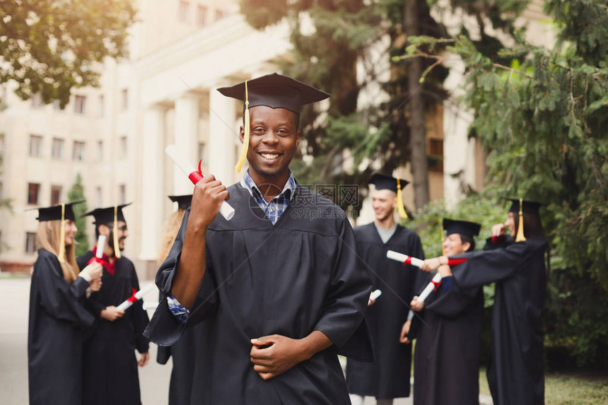 年轻微笑的非洲裔美国人在大学毕业那天与多民族学生站在一起教育资图片