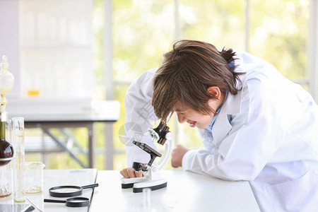 快乐的小男孩用显微镜做科学实验教育和图片