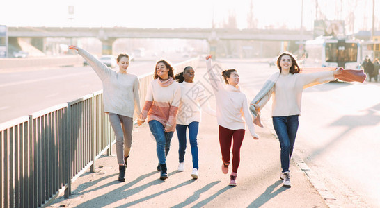 五个来自不同种族的女性朋友一起在马路旁散步图片