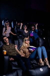 一群朋友和女友试图唤醒疲累的家伙在电影期间在电影院图片