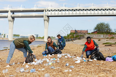 一群志愿者在户外河岸附近捡垃圾他们把图片