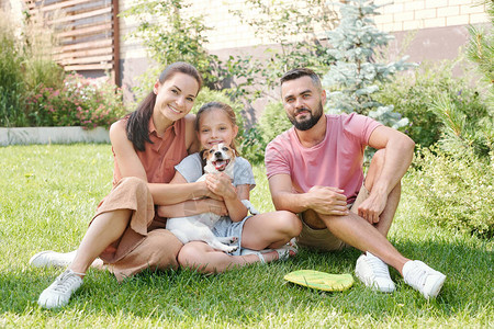 一个女儿的年轻家庭与自己的小狗在后院一起度过时间图片