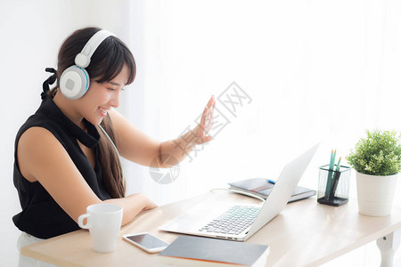 戴着耳机的女生微笑着在笔记本电脑上视频聊天图片