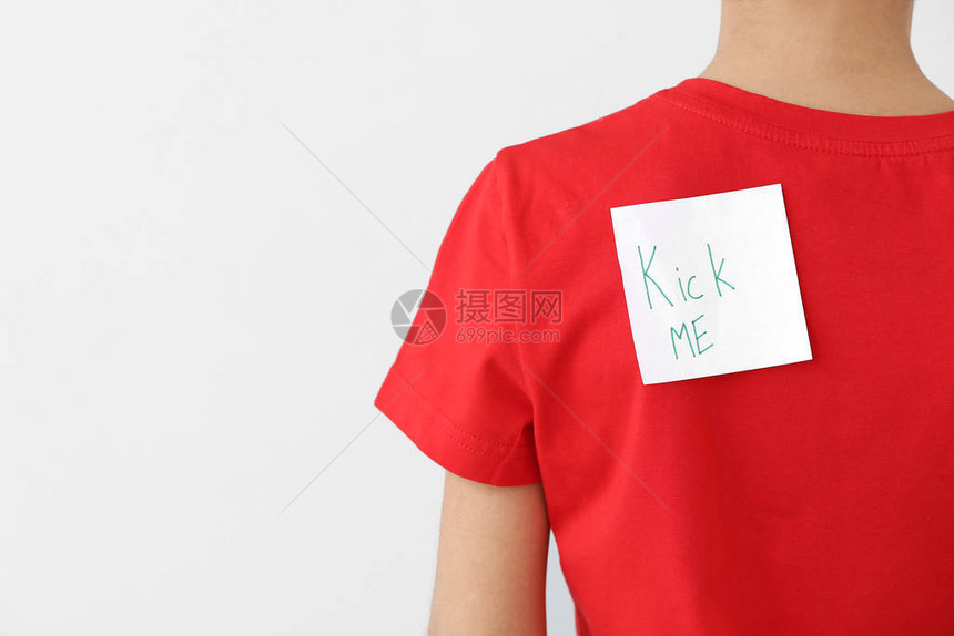 在轻背景的小男孩背上贴着短信KICKME的粘贴笔记April愚图片