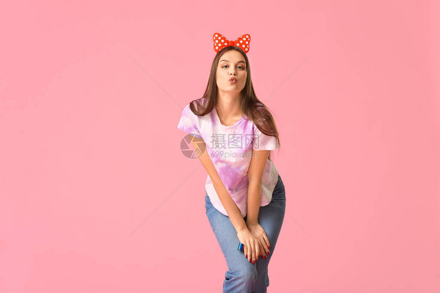 带着蝴蝶结发箍的女孩站在粉色背景墙前图片