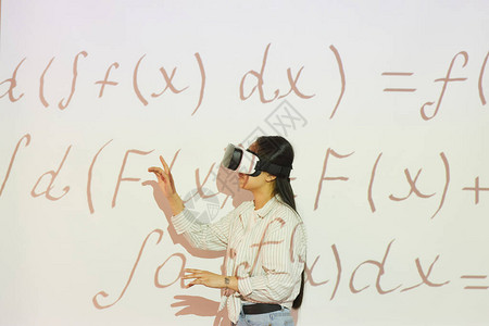 虚拟现实头盔中的Brunette学生女孩指向投影屏幕图片
