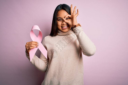 年轻的亚洲女孩拿着粉红色的癌症丝带符号图片