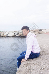 年轻男人坐在海岸港口图片