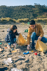 年轻志愿者在海滩捡垃圾图片