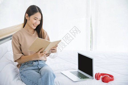 女人正坐在卧室床上看书图片