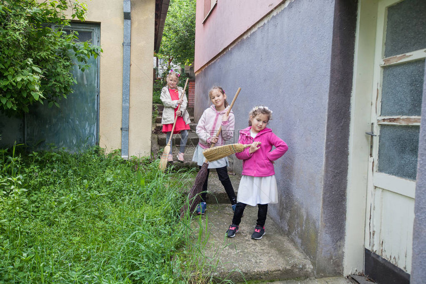 三个小女孩用扫帚打扫后院图片