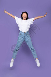 在紫色背景上开心跳跃的女孩图片