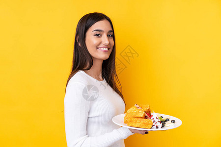 年轻的黑发年轻女人拿着华夫饼在孤立图片