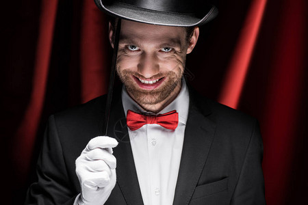 穿着西装和帽子的笑着吓人的魔术师在马戏团用红图片